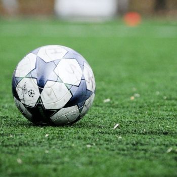 white and blue soccer ball on green grass field during daytime